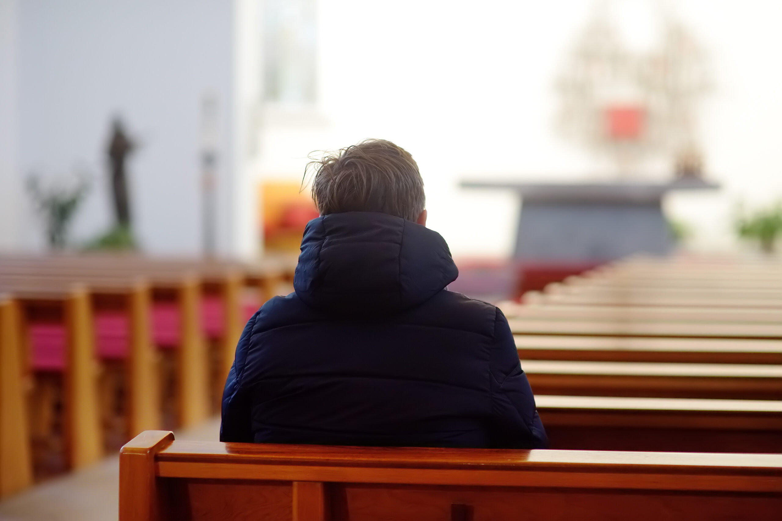 Religious middle age man praying and meditating in catholic church. Person begging for forgiveness and blessing from God.